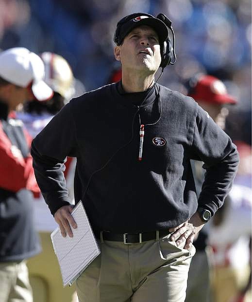 San Francisco 49ers head coach Jim Harbaugh watches the scoreboard against the Carolina Panthersduring the first half of a divisional playoff NFL football game, Sunday, Jan. 12, 2014, in Charlotte, N.C. (AP Photo/Gerry Broome)