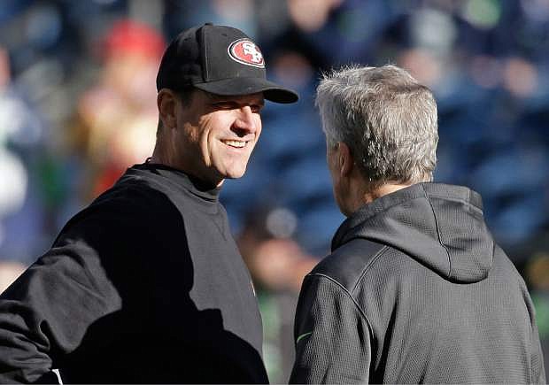 San Francisco 49ers head coach Jim Harbaugh, left, talks with Seattle Seahawks head coach Pete Carroll, right, on the field before an NFL football game, Sunday, Dec. 14, 2014, in Seattle. (AP Photo/Elaine Thompson)