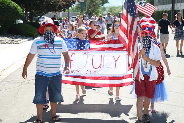 Led by nine-year-old Izaiah Cheatwood, left, and Roland List, 8, Kinderland Pre-school students parade up Sophia St. on Thursday morning in celebration of Independence Day. The annual parade loops Kinderland&#039;s neighborhood off their Curry St. address.