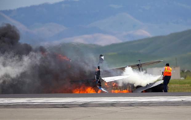 A worker fights a fire after a vintage biplane crashed upside-down on a runway at an air show at Travis Air Force Base in Fairfield, Calif., Sunday, May 4, 2014. The pilot, Edward Andreini, 77, of Half Moon Bay, was killed when the plane, flying low over the tarmac, crashed and caught fire. (AP Photo/Bryan Stokes)