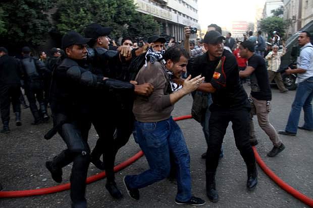 Egyptian police arrest a protester in Cairo, Tuesday, Nov. 26, 2013, after they fired water cannons to disperse two protests by dozens of secular anti-government activists, the security forces&#039; first implementation of a controversial new law forbidding protests held without a permit from authorities. (AP Photo/Ahmed Gomaa)