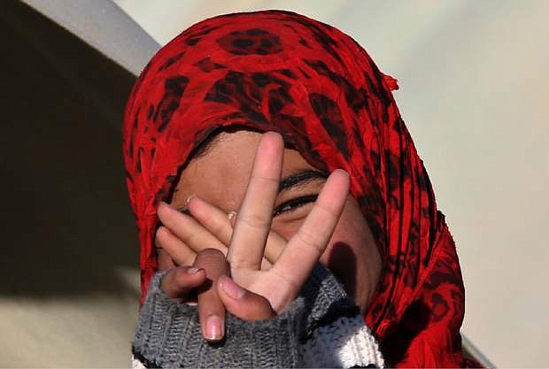 A Syrian girl flashes victory sign at a refugee camp in the eastern Lebanese border town of Arsal, Lebanon, Friday, Nov. 29, 2013. Every morning in northeastern Lebanon, hundreds of Syrian children are picked up from dozens of informal refugee settlements, loaded onto trucks and taken to the fields where they work for six to eight hours, earning up to four dollars a day. The kids are among a growing number of Syrian refugee children in Lebanon and Jordan who are fast becoming primary providers for families who lack resources for basic survival, according to a newly released report by the U.N. refugee agency. (AP Photo/Hussein Malla)