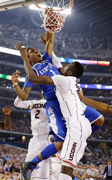 Kentucky guard James Young (1) dunks between Connecticut forward DeAndre Daniels (2) and center Amida Brimah (35) during the second half of the NCAA Final Four tournament college basketball championship game Monday, April 7, 2014, in Arlington, Texas. (AP Photo/David J. Phillip)