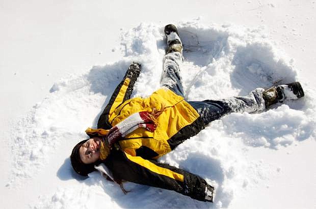 Dallas Gray, 8, makes a snow angel during a break from sledding on Sunday, Dec. 22, 2013, in Hutchinson, Kan. (AP Photo/The Hutchinson News, Lindsey Bauman)
