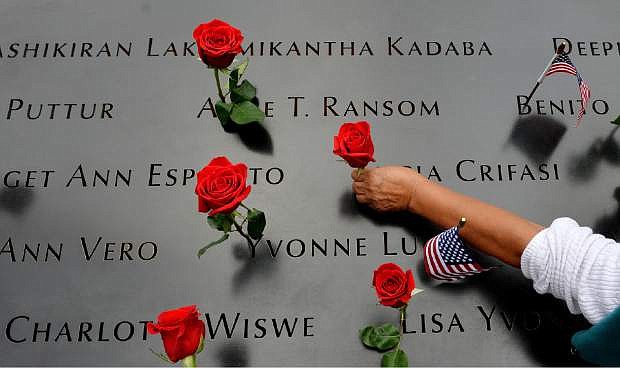 A woman places flowers in the inscribed names along the edge of the North Pool during memorial observances on the 13th anniversary of the Sept. 11 terror attacks on the World Trade Center in New York, Thursday, Sept. 11, 2014.   In New York, family members of those killed at the World Trade Center will read the names of the victims at a ceremony at ground zero.  (AP Photo/Justin Lane, Pool)