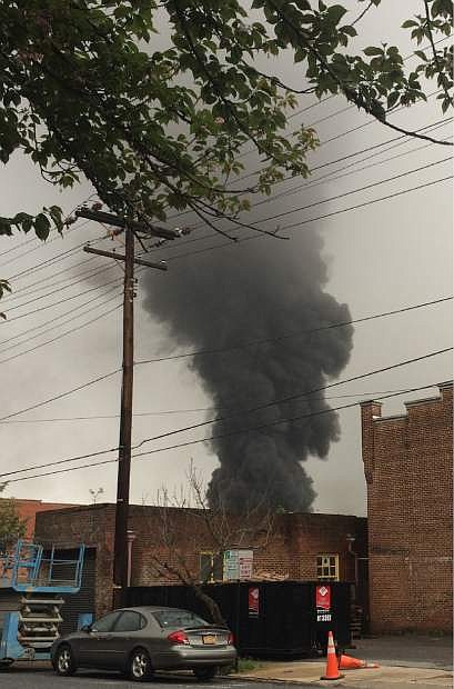 In this mobile phone photo provided Charles Peters, smoke rises after several CSX tanker cars carrying crude oil derailed on Wednesday, April 30, 2014, in Lynchburg, Va. Authorities evacuated numerous buildings Wednesday after the derailment. (AP Photo/Charles Peters) MANDATORY CREDIT