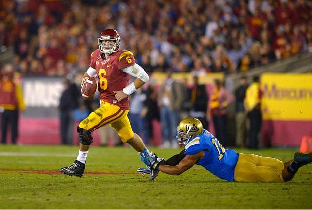 Southern California quarterback Cody Kessler (6) escapes a tackle by UCLA linebacker Anthony Barr during the first half of an NCAA college football game, Saturday, Nov. 30, 2013, in Los Angeles. (AP Photo/Mark J. Terrill)