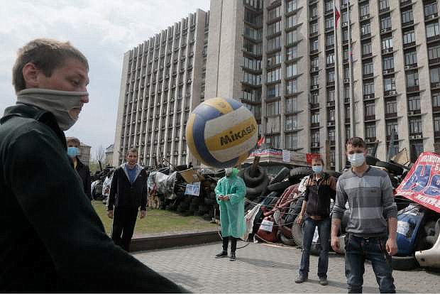 Masked pro-Russian activists play with a  ball as they guard a barricade at the regional administration building that they had seized earlier in Donetsk, Ukraine, Saturday, April 19, 2014. Pro-Russian insurgents defiantly refused Friday to surrender their weapons or give up government buildings in eastern Ukraine, despite a diplomatic accord reached in Geneva and overtures from the government in Kiev. (AP Photo/Efrem Lukatsky)