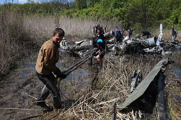 Local citizens collect parts of a downed Ukrainian military helicopter near a small town Raigorodok, outside Slovyansk, Ukraine, Tuesday, May 6, 2014. The helicopter was forced to make an emergency landing Monday during intense fighting in Slovyansk and was later destroyed by Ukrainian troops, who sought to ensure it did not fall into the hands of insurgent forces. (AP Photo)