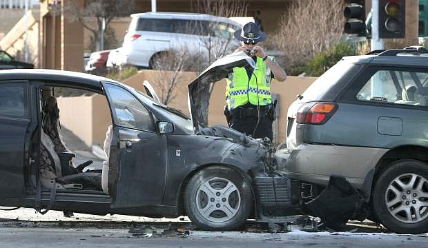 A NHP officer investigates the scene of a 2-vehicle crash on south Carson Street on Monday afternoon.