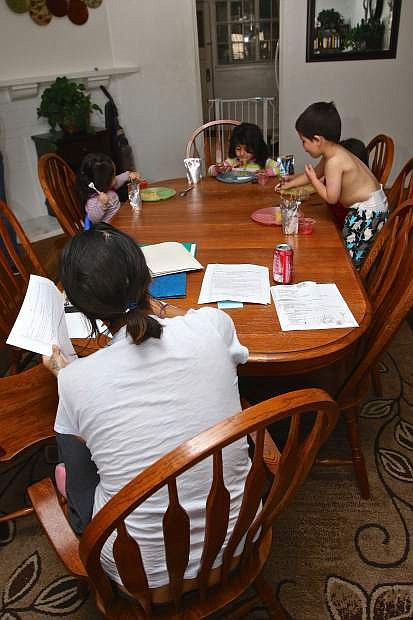 Sheltered children have a meal while mom works on homework in an Advocates safe house Thursday in Carson City.