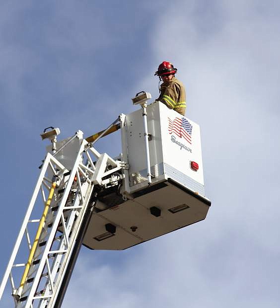 Two firefighters sit in the bucket atop an aerial ladder nearly 100 feet in the air. The firefighters are practicing their &quot;ladder day&quot; in Carson City as a part of the Fire Academy Wednesday.