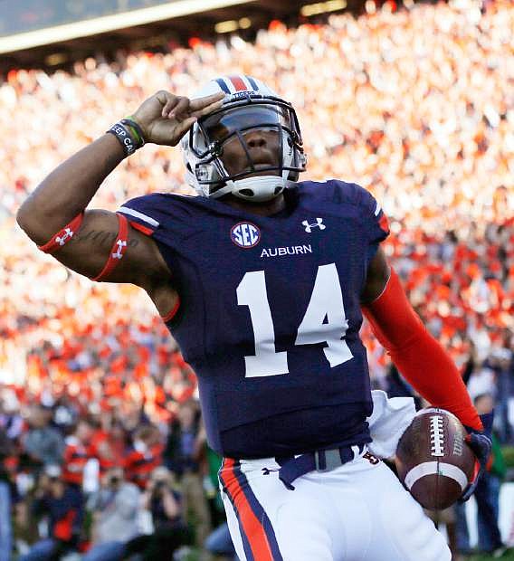 Auburn quarterback Nick Marshall (14) salutes after scoring against Alabama on a 45-yard touchdown run in the first half of an NCAA college football game in Auburn, Ala., Saturday, Nov. 30, 2013. (AP Photo/Dave Martin)