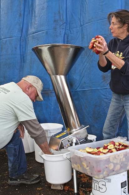 Laura Barrett of Carson City and Greenhouse Garden Center employee Robert Reynolds of Gardnerville load apples into the crusher to make pulp to put in the juice press. The public was allowed to bring in clean apples to make into apple juice at the event Saturday.