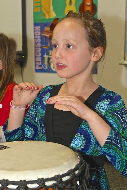Braelynn Hudson, 7, plays a bongo drum during class Friday at Mark Twain Elementary.