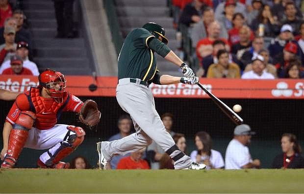 Oakland Athletics&#039; Brandon Moss, right, hits a three-run home run as Los Angeles Angels catcher Chris Iannetta watches during the fourth inning of a baseball game, Wednesday, April 16, 2014, in Anaheim, Calif. (AP Photo/Mark J. Terrill)