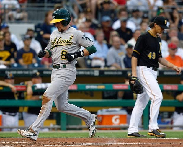 Oakland Athletics&#039; Jed Lowrie (8) scores from third on a sacrifice fly by Josh Donaldson past Pittsburgh Pirates starting pitcher Jeff Locke (49) in the fourth inning of the baseball game on Monday, July 8, 2013, in Pittsburgh. (AP Photo/Keith Srakocic)
