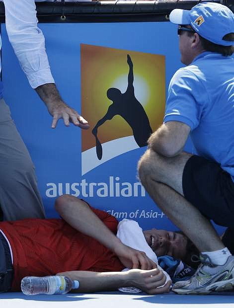 Frank Dancevic of Canada lies on the court after collapsing during his first round match against Benoit Paire of France as temperatures topped at 43 C (108 F) at the Australian Open tennis championship in Melbourne, Australia, Tuesday, Jan. 14, 2014. (AP Photo/Aijaz Rahi)