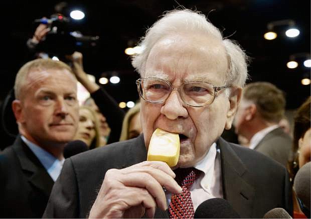 Berkshire Hathaway Chairman and CEO Warren Buffett eats an ice cream bar while touring the exhibition floor prior to the annual shareholders meeting on Saturday, May 3, 2014, in Omaha, Neb. More than 30,000 shareholders are expected to fill the CenturyLink Arena to hear Buffett and Berkshire Vice Chairman Charlie Munger discuss their business. (AP Photo/Nati Harnik)