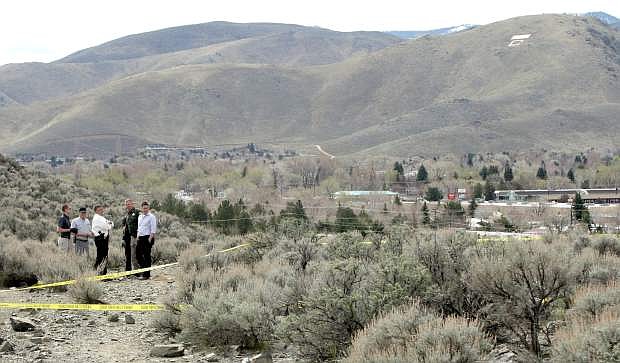 Investigators meet at the site where a hiker discovered a body buried in a shallow grave on Tuesday.