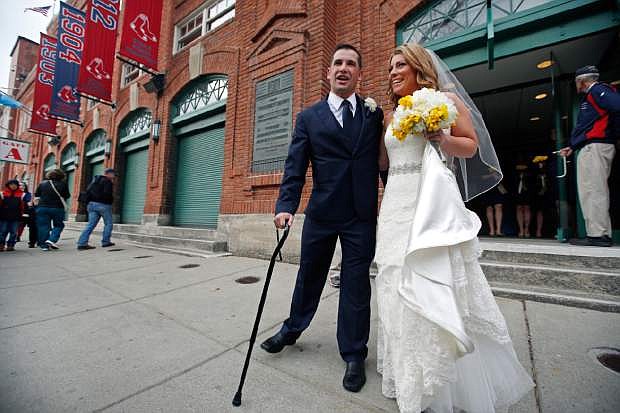 Boston Marathon bombing survivor Marc Fucarile and his bride, Jennifer Regan, leave after their wedding ceremony at Fenway Park in Boston, Thursday, April 17, 2014. Fucarile, a 35-year-old roofer, lost his right leg from above the knee in the bombing. (AP Photo/Elise Amendola)