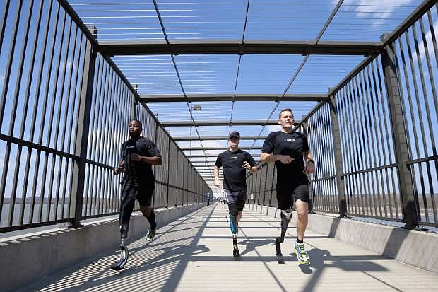 In this photo taken March 29, 2014, amputee marathon runners Andre Slay, left, Chris Madison, center, and Jeff Glasbrenner train on a footbridge aver the Arkansas river in Little Rock, Ark. (AP Photo/Danny Johnston)