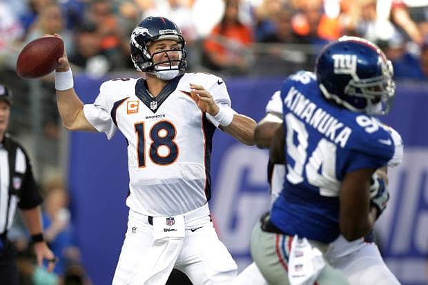 Denver Broncos quarterback Peyton Manning (18) throws a pass during the first half of an NFL football game as New York Giants linebacker Mathias Kiwanuka (94) rushes the passer Sunday, Sept. 15, 2013, in East Rutherford, N.J. (AP Photo/Kathy Willens)