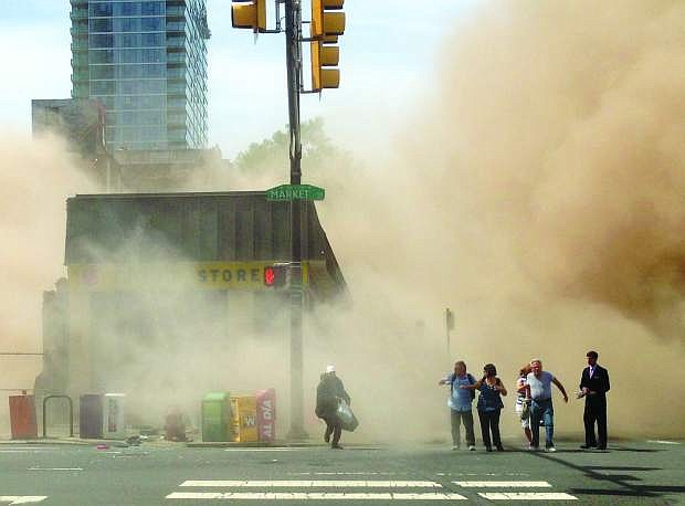 In this photo provided by Jordan McLaughlin, a dust cloud rises as people run from the scene of a building collapse on the edge of downtown Philadelphia on Wednesday, June 5, 2013.  Buoyed by the discovery of a woman buried in rubble nearly 13 hours later, rescue workers on Thursday were digging through the debris from the building collapse that killed six people a day earlier.  (AP Photo/Jordan McLaughlin)