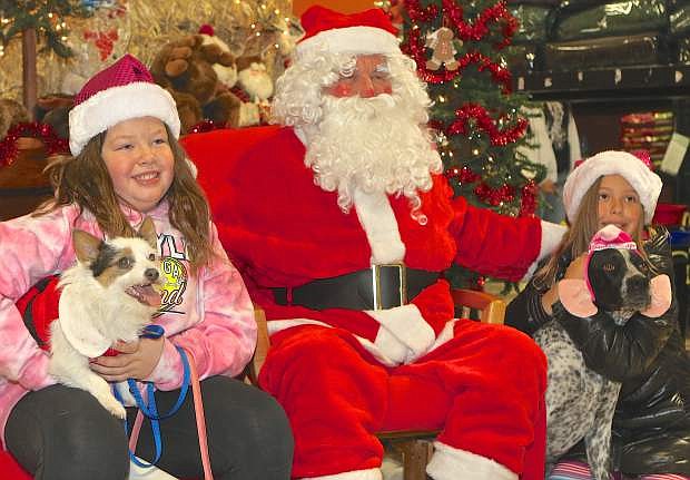 Kate Pattison, 9, and Helen Sheldon, 10, along with dogs Chloe and Zeta pose for a picture with Santa Saturday morning at Benson&#039;s Feed. The event was a fundraiser for the Carson Animal Services Initiative.