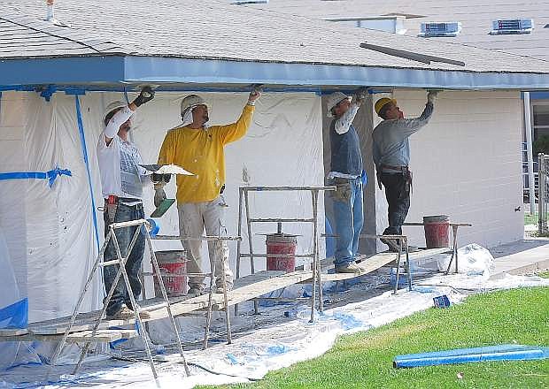 Painters add their touch Thursday to the south wall at Northside Early Learning Center, while construction workers are busy replacing the roof at another building.