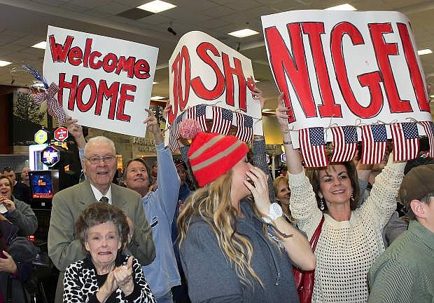 Family and friends, many of whom are from Carson City, wave signs welcoming home Chief Warrant Officer Josh Groth and 1Lt. Nigel Harrison.