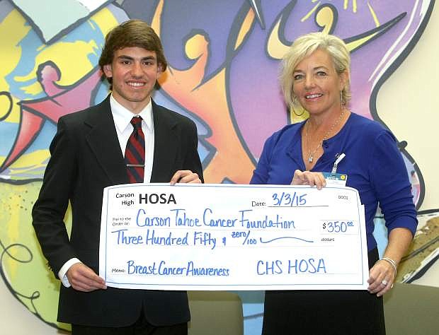 Carson High School senior Michael Leiken, who is president of the school&#039;s HOSA club presents a $350 check to Kitty McKay of the Carson Tahoe Cancer Center on Tuesday. Members of HOSA sold breast cancer awareness lanyards to raise money for breast cancer awarness and research.