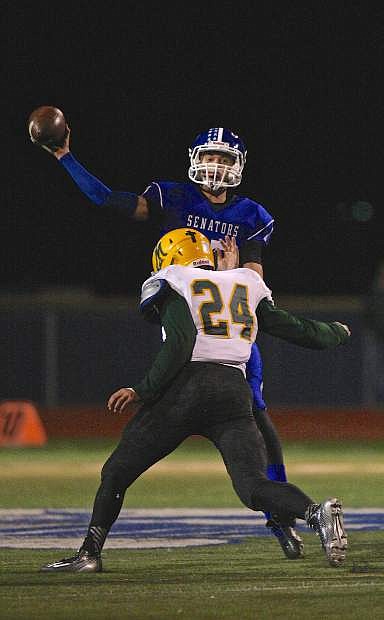 Carson QB Joe Nelson let&#039;s one fly just before getting hit by Manogue&#039;s Wes Farnsworth (24) Friday night at CHS.
