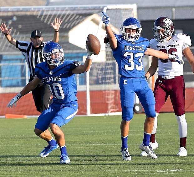 Brandon Gagnon (10) holds up the ball he intercepted while Spencer Rogers (33) indicates the change of posession Saturday night against Desert Mountain.