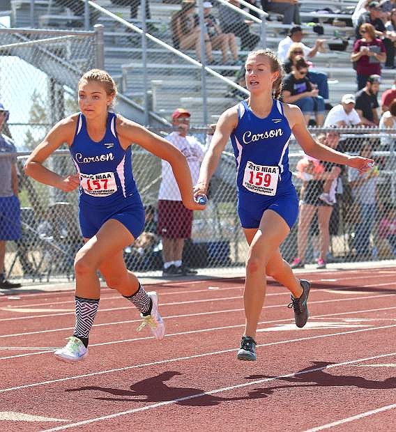 Athena Favero (left) takes the stick from a relay teammate last season at the state track meet in Las Vegas.