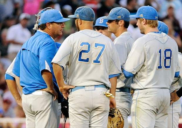 UCLA coach John Savage, left, speaks to pitcher Adam Plutko, center right, on the mound in the fourth inning of Game 1 in their NCAA College World Series baseball finals against Mississippi State, Monday, June 24, 2013, in Omaha, Neb. (AP Photo/Francis Gardler)