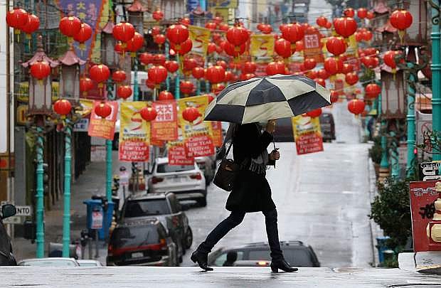 A woman carries an umbrella as she crosses the street with lanterns from Chinatown hanging behind her in San Francisco, Friday, Feb. 7, 2014. Dry California got a much needed taste of rain, but drought-watchers hope it was just a teaser for a much wetter weekend. A bigger storm expected to arrive late Friday and last through Sunday could dump as much as 2 feet of snow on the slopes of the Sierra and 6 inches of rain on San Francisco Bay Area mountains. (AP Photo/Jeff Chiu)