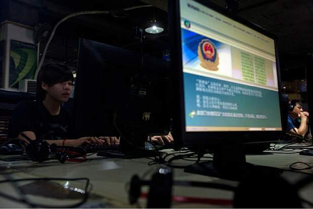 FILE - In this Monday, Aug. 19, 2013 file photo, computer users sit near a display with a message from the Chinese police on the proper use of the internet at an internet cafe in Beijing, China. The Chinese government has declared victory in its recent campaign to clean up what it considers rumors, negativity and unruliness from online discourse, while critics say the moves have suppressed criticism of the government and ruling Communist Party. (AP Photo/Ng Han Guan, File)