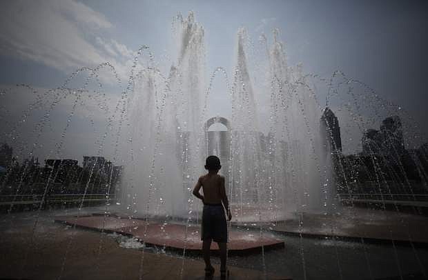 A boy cools off in a fountain at a park in Shanghai, China, Thursday, Aug. 1, 2013.  Hot weather has set in with temperatures rising up to 40 degrees Celsius (104 degrees Fahrenheit) in Shanghai. (AP Photo/Eugene Hoshiko)