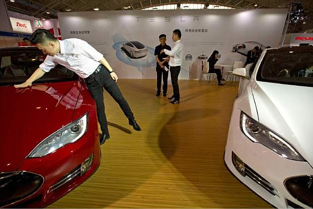FILE - In this Monday, April 25, 2016, file photo, a staff member cleans the hood of a Tesla Model S electric car near a display advertising Tesla&#039;s self-driving features at the Beijing International Automotive Exhibition in Beijing, China. Tesla says it can&#039;t verify whether a vehicle autopilot system is to blame for the death of a Chinese man whose father claimed in a report broadcasted Wednesday, Sept. 14, 2016, on state television that the driver-assist feature was active at the time of his crash. (AP Photo/Mark Schiefelbein, File)