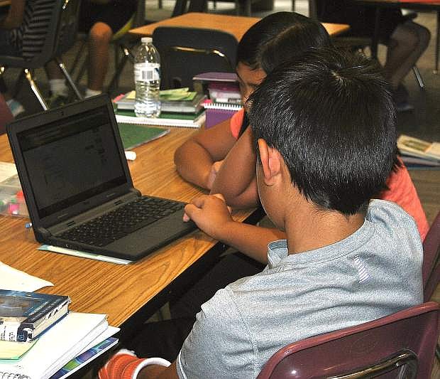 Fifth-grade students in Kevin Wickware&#039;s class share a chrome book during a project.
