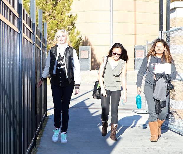 Carson High students Chauntel Bennett, Amanda Yau and Marjourie Peralta walk in between the new security fence and a temporary construction fence Thursday afternoon at CHS.