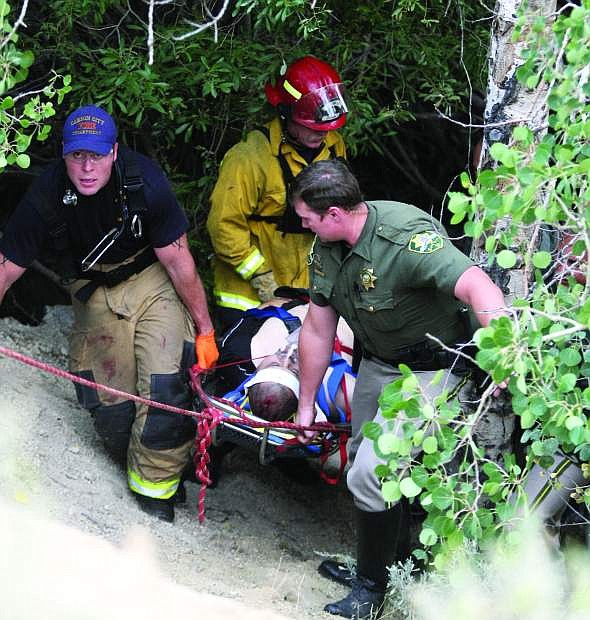 Carson City sheriff&#039;s deputies, firefighters and paramedics carry a man up an embankment near Clear Creek Road on Friday evening after he fell while rock climbing.