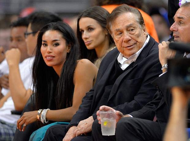 FILE - In this file photo taken on Friday, Oct. 25, 2013, Los Angeles Clippers owner Donald Sterling, right, and V. Stiviano, left, watch the Clippers play the Sacramento Kings during the first half of an NBA basketball game in Los Angeles. Used car dealership chain CarMax says it is ending its sponsorship of the Clippers in the wake of racist comments attributed to Sterling. (AP Photo/Mark J. Terrill, File)