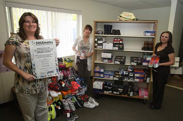 Peggy Sweetland, center,director of the Carson City School District&#039;s Children In Transition program, displays a pair of shoes collected through the Soulmate shoe drive, sponsored by assisted living community, The Lodge. Gina Hein, left, mission coordinator for The Lodge, helped organize the shoe drive. Samantha Hefner is office manager for the Children In Transition program, which is kicking off its winter coat drive.