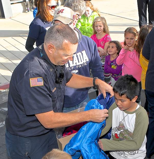 Carson City Fire Capt. Jason Danen helps 7-year-old Joshua Flores try on his new jacket during the 2015 Coats for Kids campaign.