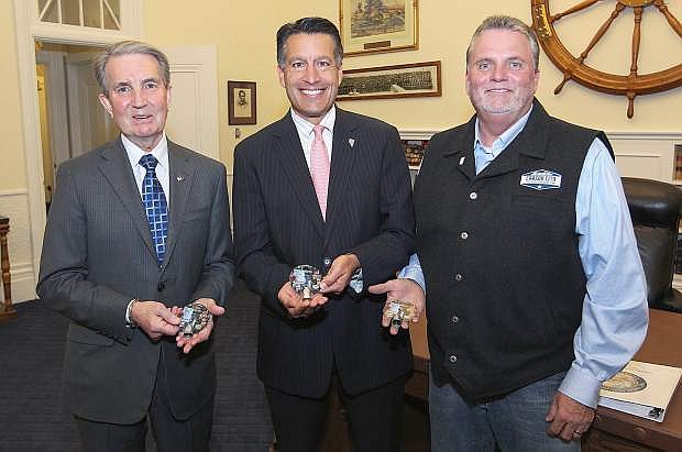 Mayor Bob Crowell, left, and Carson City Visitors Bureau Director Joel Dunn, right, present Gov. Brian Sandoval with the first in a series of limited edition, commemorative Sesquicentennial bells, at the Capitol. The bells are available for sale at the Visitors Bureau at 716 N. Carson Street beginning on Monday.