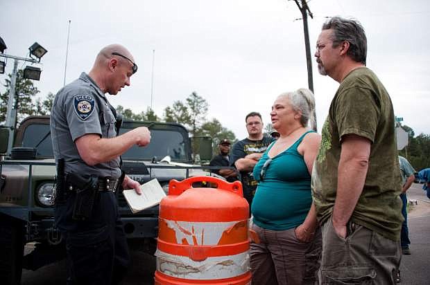A police officer helps manage escorts into the burn zone for residents to retrieve animals and medication at a roadblock on Friday, June 14, 2013 near Colorado Springs, Colo.  Little more than 36 hours after it started in the Black Forest area northeast of Colorado Springs, the blaze surpassed last June&#039;s Waldo Canyon fire as the most destructive in state history. That blaze burned 347 homes and killed two people.  Bradley thinks her home escaped the fire.  (AP Photo/The Gazette, Michael Ciaglo)