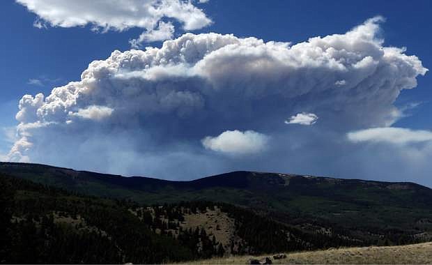 Wildfire smoke plumes above Del Norte Peak on Sunday, June 23, 2013, in near Del Norte, Colo. A large wildfire near a popular summer retreat in southern Colorado continues to be driven by winds and fueled by dead trees in a drought-stricken area, authorities said Sunday. (AP Photo/Gregory Bull)