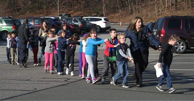 FILE - In this photo provided by the Newtown Bee, Connecticut State Police lead a line of children from the Sandy Hook Elementary School in Newtown, Conn. on Friday, Dec. 14, 2012 after a shooting at the school.  Recordings of 911 calls from the Newtown school shooting are being released Wednesday Dec. 4, 2013, days after a state prosecutor dropped his fight to continue withholding them despite an order to provide them to The Associated Press. (AP Photo/Newtown Bee, Shannon Hicks, File) MANDATORY CREDIT: NEWTOWN BEE, SHANNON HICKS